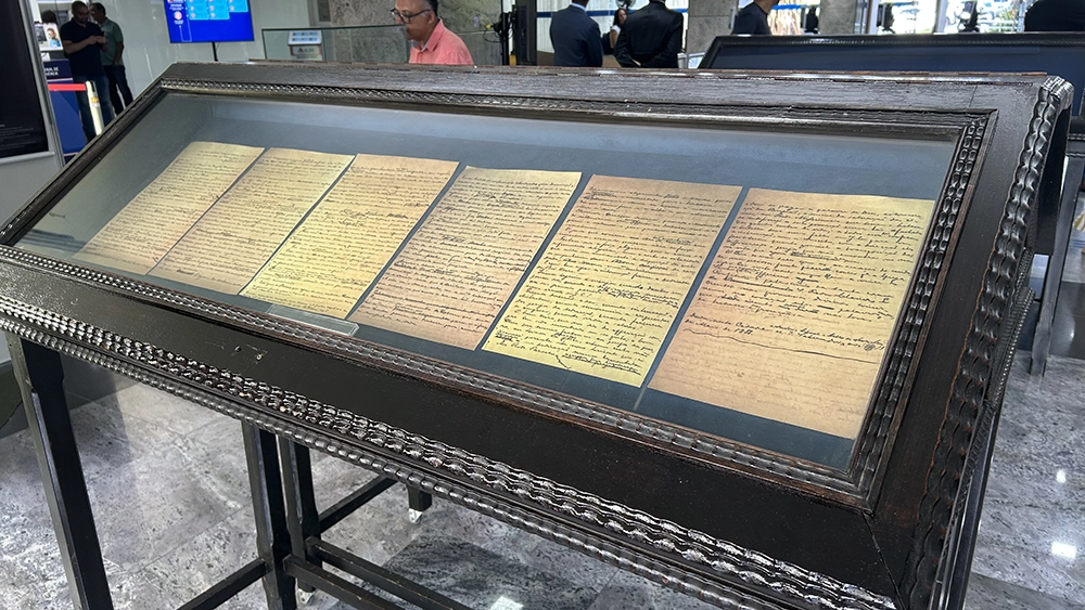 Vitrine expositora com seis documentos manuscritos antigos, de papel amarelado, abertos lado a lado.